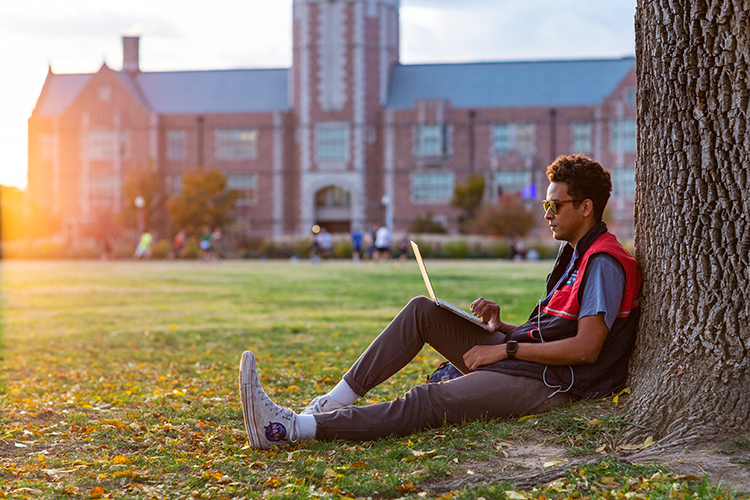 Student sitting by tree on campus